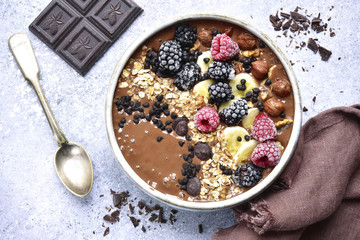 Chocolate banana smoothie bowl with frozen berries and granola.Top view.