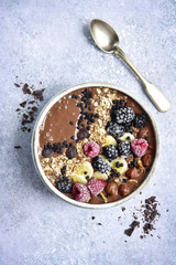 Chocolate banana smoothie bowl with frozen berries and granola.Top view.