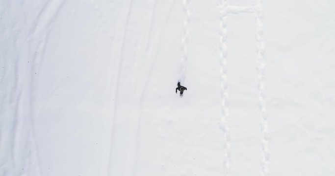 Overhead aerial top view over man walking with snowshoes on white snow covered field in winter.Europe Alps outdoor nature scape snowy mountains.4k drone flight straight-down perspective
