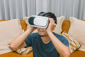 A man wearing virtual reality enjoying in VR glasses use smartphone on sofa, Innovation technology