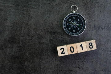 Compass and wooden block number 2018 on dark black background as year 2018 prediction or direction concept
