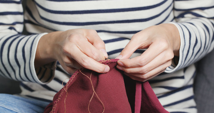 Woman Sews With A Needle And Thread