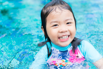 Pretty little asian girl happy in swimming pool.