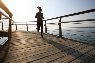 sporty female jogger morning exercise on seaside boardwalk during sunrise