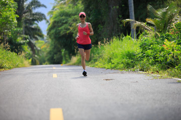 fitness female runner running on tropical forest trail