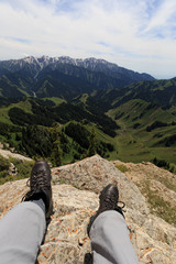 Hiker legs sit on mountain top cliff edge