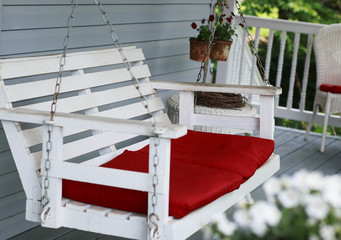 White porch swing with red cushions
