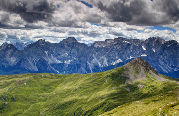 Sunlit gentle grassy slopes of Carnic Alps with limestone wall of Sesto Dolomiti, Col Quaterna, Cima Bagni, Monte Popera, Undici and Croda Rossa peaks, Belluno Bolzano Alto Adige Sudtirol Italy Europe