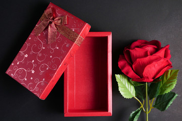 Empty red gift box with red rose on black background. Concept of Valentine Day.