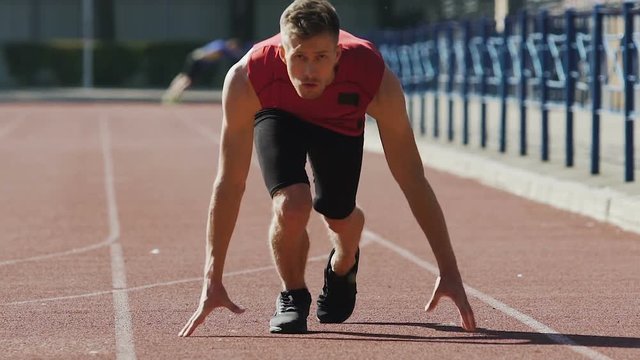 Guy getting to start position and beginning to run, preparation for marathon
