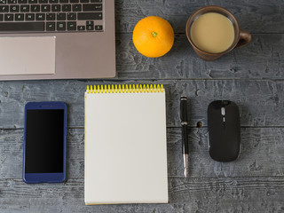 Notebook, notebook, pen, orange, phone and coffee Cup on the dark wooden table.