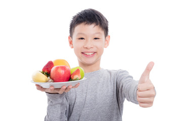 Young asian boy holding fruits and smiles over white background