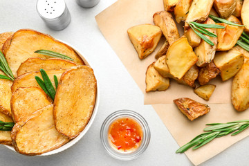 Composition with bowl of tasty rosemary potatoes on table