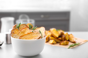 Bowl of tasty rosemary potatoes on table