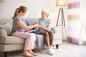 Caregiver giving glass of water to senior woman at home - Powered by Adobe