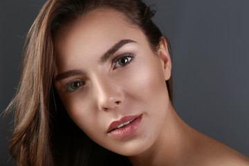 Fototapeta premium Beautiful young woman with eyelash extensions on grey background