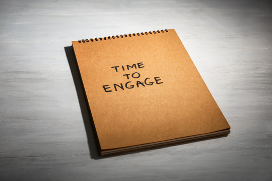 Notebook with written phrase TIME TO ENGAGE on wooden background
