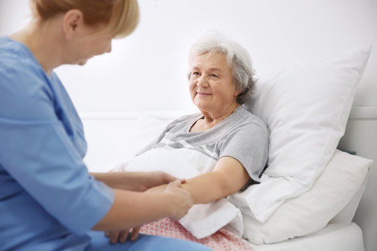 Caregiver massaging hand of senior woman at home