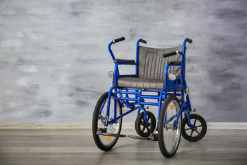 Fototapeta na wymiar Blue wheelchair near grey wall indoors