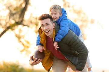 Father with little son playing rugby outdoors