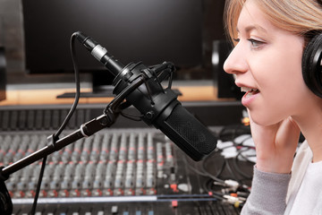 Female radio host broadcasting through microphone in studio