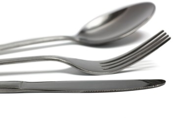 Knife, Fork and Spoon closup on White. Focus on knife