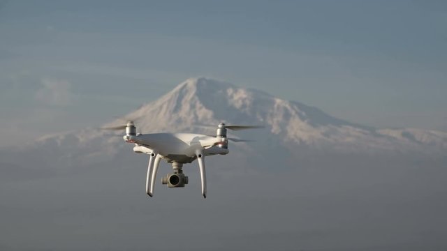 Aircraft drone pilot flight over natural winter scenic place isolated closeup, at background white big cliff ridge. Radio-controlled multirotor helicopter, working by wireless, no people around