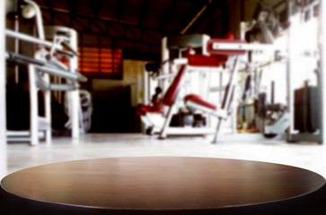 Wooden table on blurred background of fitness gym interior of modern club with equipment for your photomontage or product display.