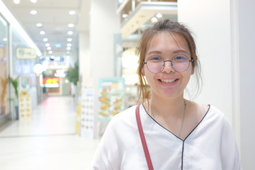 Closeup of young Asian woman with blur shopping mall background.