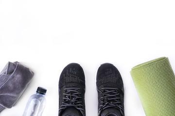Top view of fitness accessories on white background with copy space, black sneaker, bottle, towel...