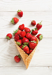 Strawberry explosion. Photo of strawberry in waffle cone on white wooden table. Top view. High resolution product.
