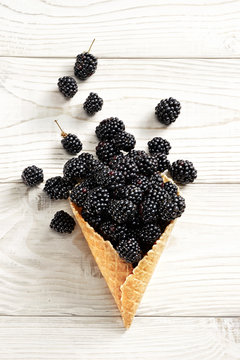 Blackberry explosion. Photo of blackberry in waffle cone on white wooden table. Top view. High resolution product.