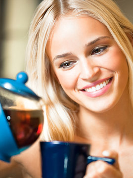 Happy girl with teapot and cup, at home