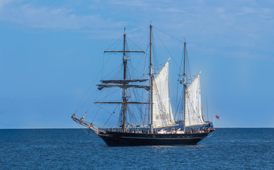 Fototapeta na wymiar Large schooner sailboat yacht anchored in bay against blue sky 