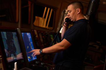 Fototapeta na wymiar Pilot / Navigator on the bridge during night hours doing his day-to-day job with binoculars and radio