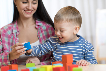 Pretty woman and her son child playing with building blocks