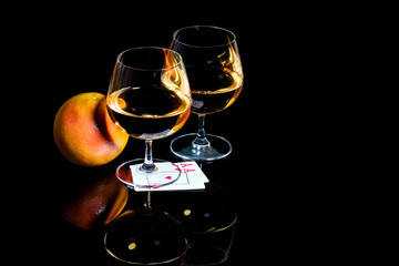 Snifters brandy with playing cards and grapefruit on black background