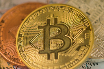 Golden Bitcoin Coin close up together with silver bitcoin and bronze bitcoin with blurred background of United States map.