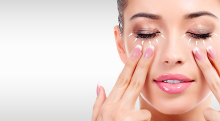 Closeup shot of young beauty woman massaging her face. Facial massage concept. Pretty girl against...
