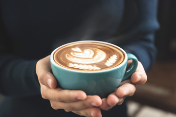 Woman hands giving a cup of latte art coffee
