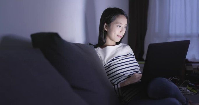 Woman using laptop computer at home in the evening