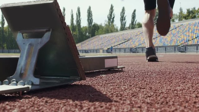 Athlete beginning to run from starting blocks at competition, slow-motion