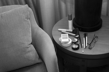 makeup, brushes and glasses on a table next to a chair