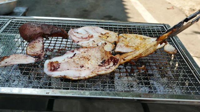 Grilled squid on a BBQ grill made of stainless steel.