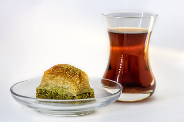 Baklava with pistachio and turkish cup of tea on a white background