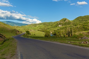 Road on the background of green meadows, mountains and sky. Road in the background of green meadows.journey to Georgia