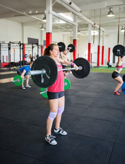 Fototapeta na wymiar Determined Woman Lifting Barbell In Gym