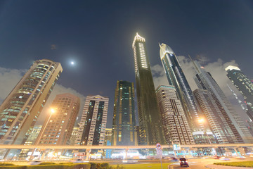 Fototapeta na wymiar DUBAI, UAE - DECEMBER 11, 2016: Downrtown skyline along Sheikh Zayed Road at night as seen from rooftop. The city attracts 30 million tourists annually