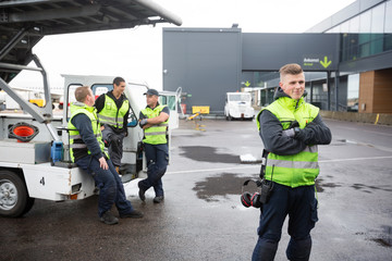 Confident Worker Standing Arms Crossed While Colleagues Communic
