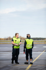 Fototapeta premium Workers In Reflective Jackets Standing On Airport Runway